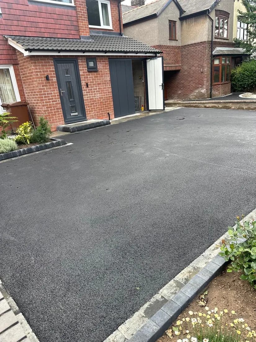 Smooth tarmac driveway approach with a block paving threshold at the entrance