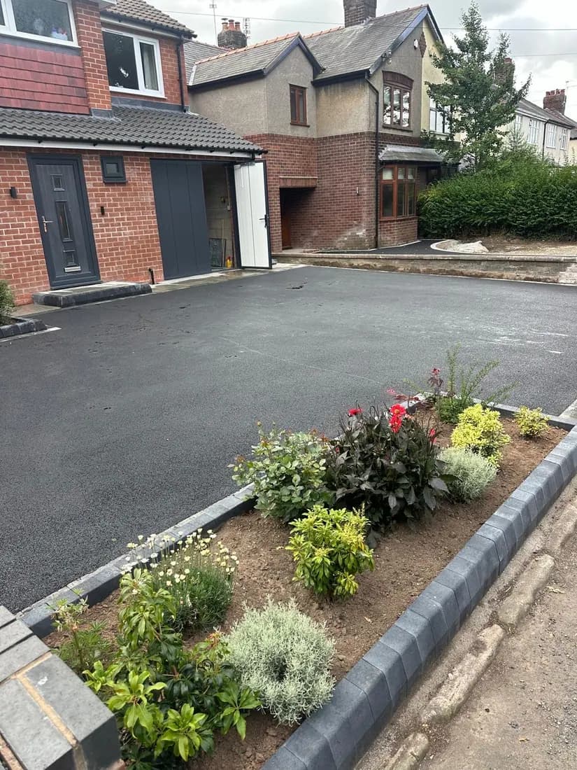 Tarmac driveway with a kerbed planting bed separating it from the pavement