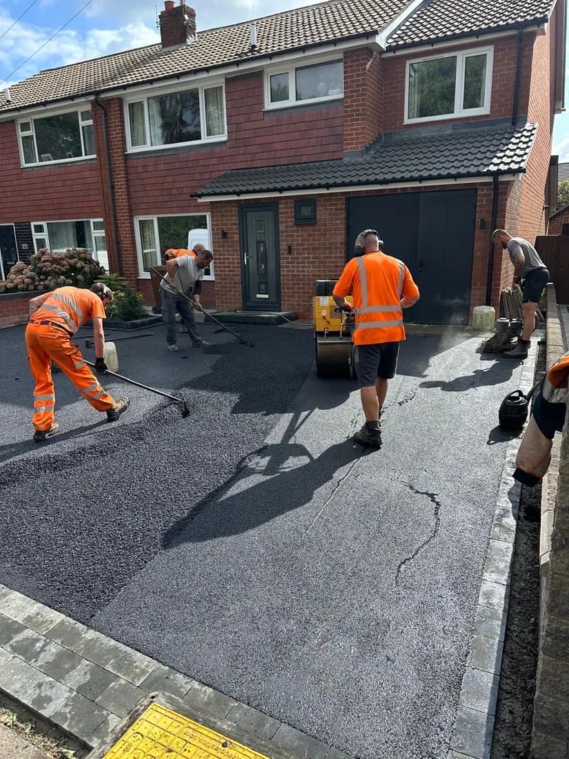 The Cheshire Paving Solutions team in hi-vis uniform raking and rolling a new tarmac driveway