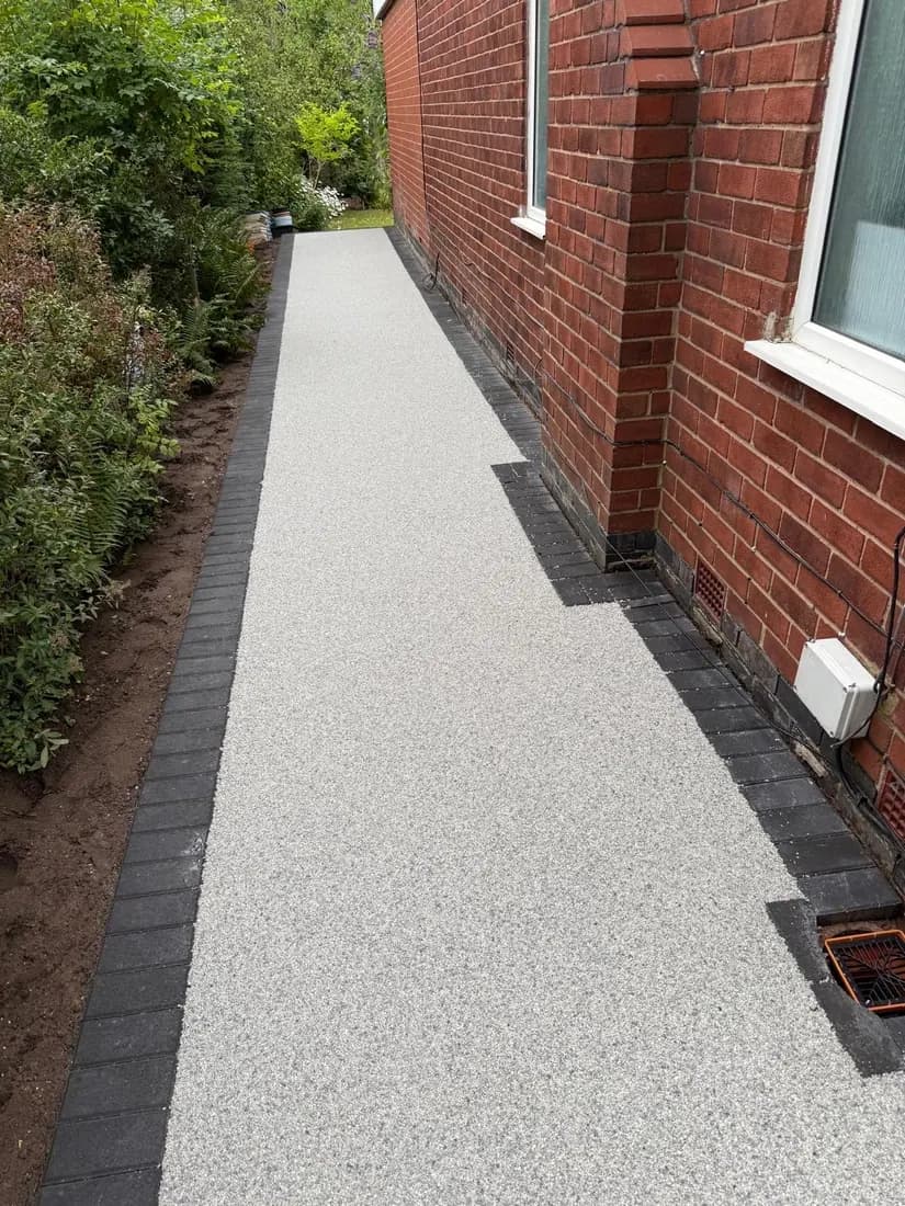 Resin bound path laid tight to a brick elevation along a narrow South Manchester side return